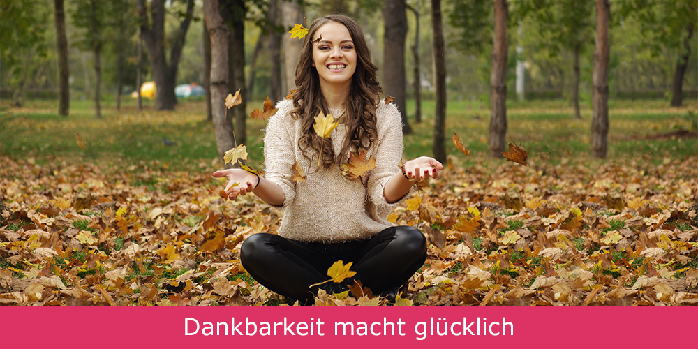 Diese Frau praktiziert Dankbarkeit und wirft mit Blättern im Herbst.